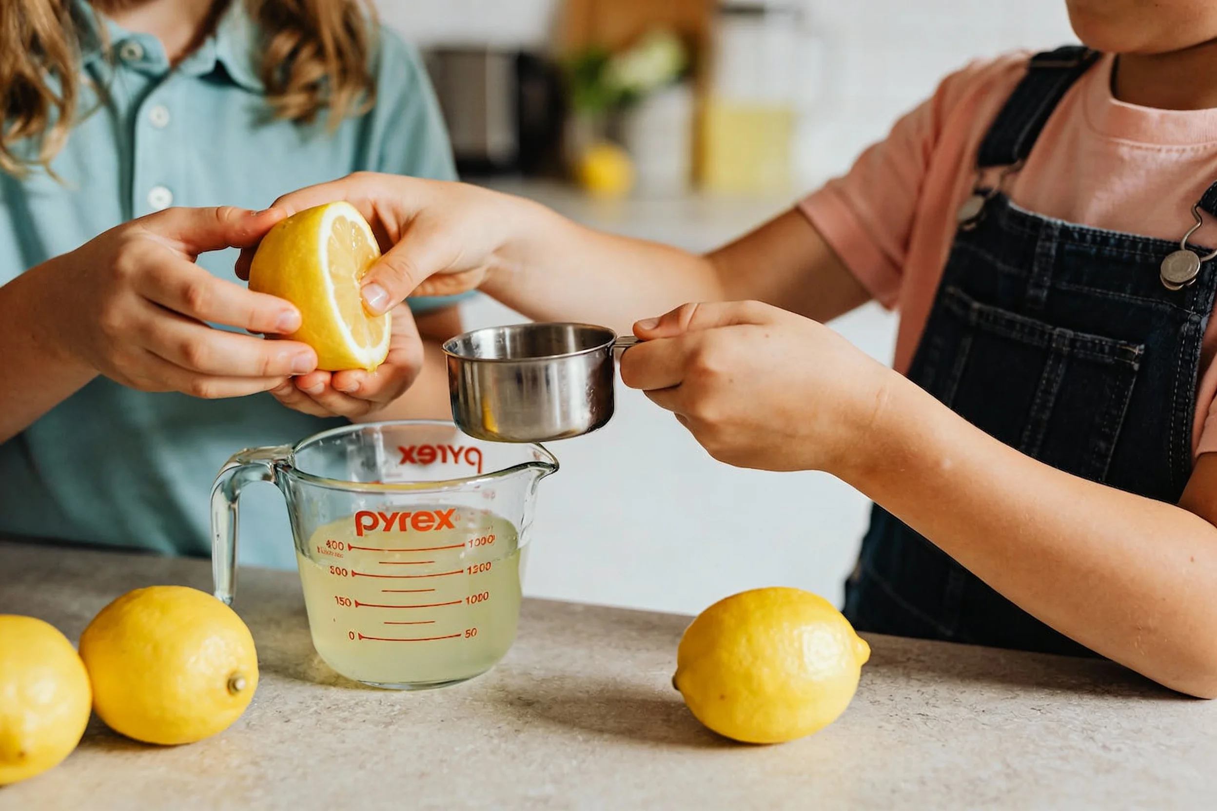 Kids making lemonade with lemons and measuring cups